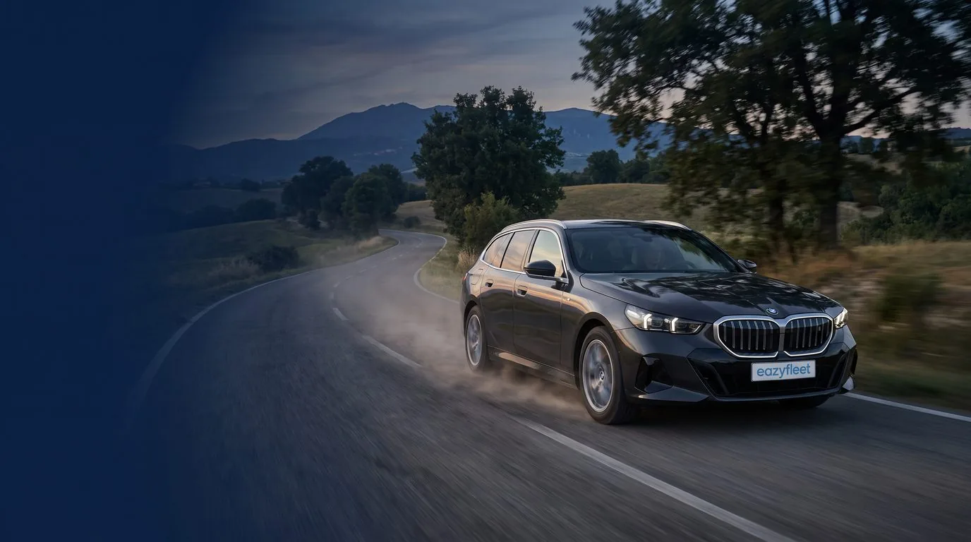 BMW 540d xDrive Touring in Oxidgrau metallic auf Schotterweg vor grünen Hügeln, Firmenwagen-Flotte im Eazyfleet Plus Abo